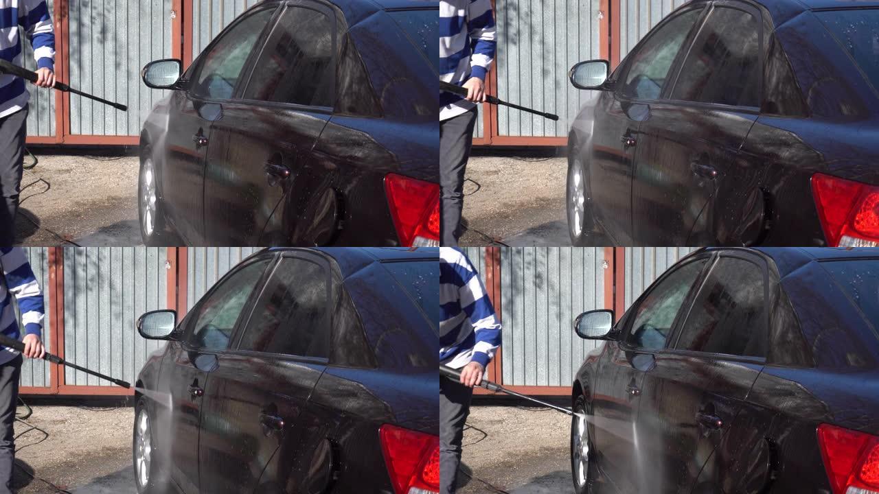 一名男子用高压水射流冲洗汽车上的污垢。洗车专用洗涤剂。在房子前面洗一辆车。