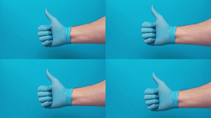 男性手在乳胶手套，拇指向上孤立在蓝色，新型冠状病毒肺炎概念