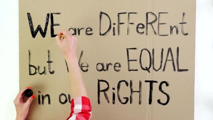 间隔拍摄。特写，手写标语，用毛笔，用黑漆在硬纸板上画横幅。我们是不同的，但我们在权利上是平等的。在美
