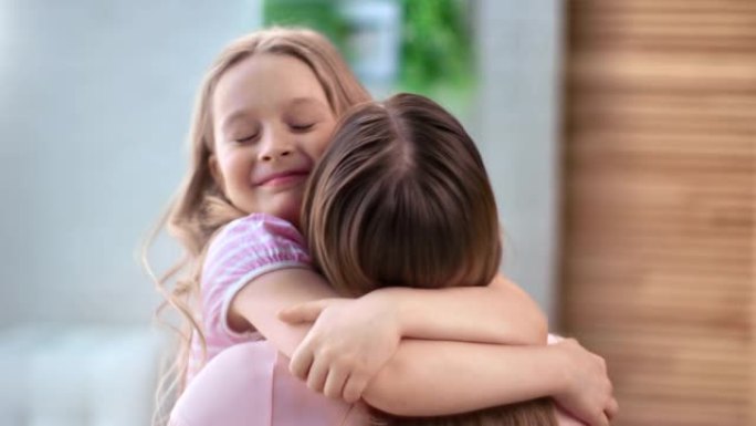 可爱的女孩拥抱母亲微笑着感受爱和积极的情感。在4k红色相机上近距离拍摄