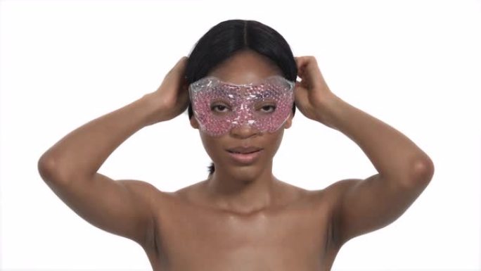 非洲女模特戴热/冷治疗珠珍珠凝胶眼罩的特写肖像镜头。化妆品。美容和保健概念