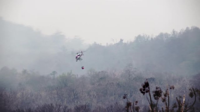 消防员直升机在森林大火中从水桶中滴水