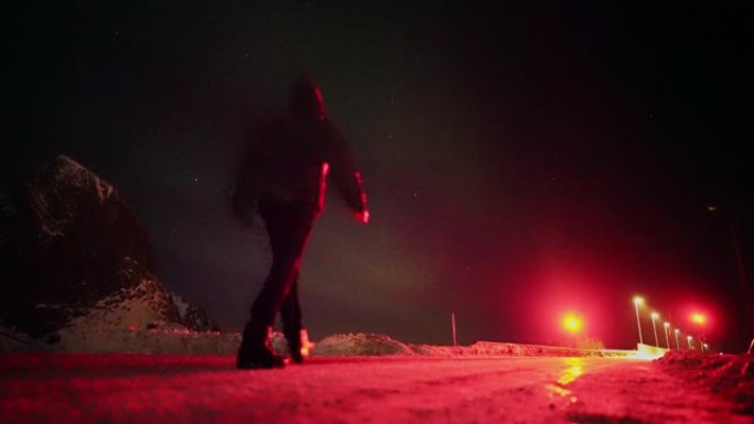 男子在冬天从公路上看着罗弗滕群岛上的北极光