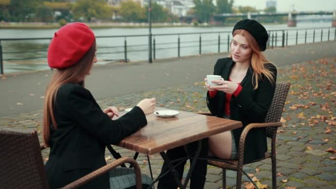 两个美丽诱人的法国女人坐在街上喝咖啡