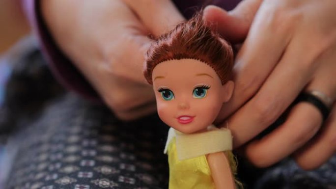 细节用母亲的手刷和整理小女儿娃娃的头发。