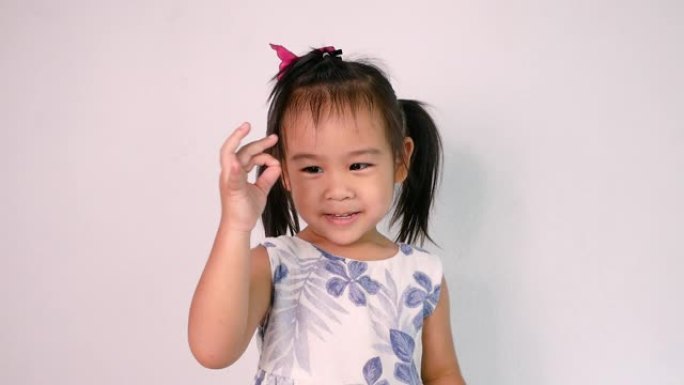 快乐的亚洲儿童女孩的肖像喜欢跳舞，并在白色背景上演唱歌曲 “小鲨鱼”。幸福家庭和童年的概念。