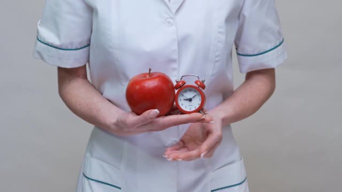 营养师医生健康生活理念 -- 手持有机红苹果和闹钟