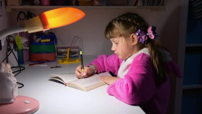 一个女孩在傍晚在台灯的灯光下做作业