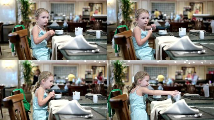 小女孩坐在一个大餐厅大厅里。