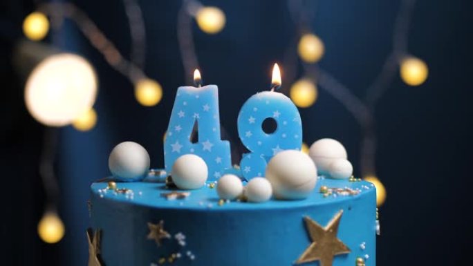 生日蛋糕编号49星星天空和月亮概念，蓝色蜡烛被打火机点燃，然后吹灭。如果需要，请在屏幕右侧复制空间。