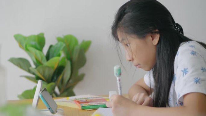 亚洲女孩在冠状病毒期间使用智能手机进行家庭教育概念。