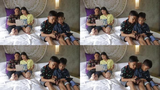 沉迷于数字技术的印度尼西亚或马拉西亚家庭。家庭使用智能手机。妈妈，爸爸和孩子们沉迷于过度使用社交媒体