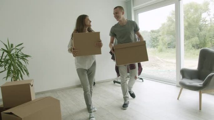 一对年轻夫妇搬着箱子在新公寓里。