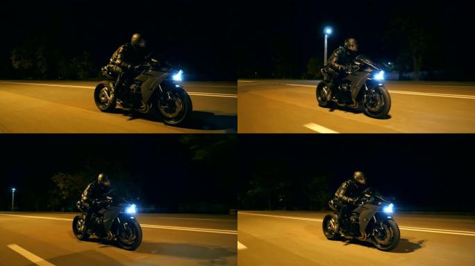 戴着头盔的年轻人在晚上的城市街道上快速骑现代黑色运动摩托车。摩托车手在夜间空旷的道路上骑摩托车。开车