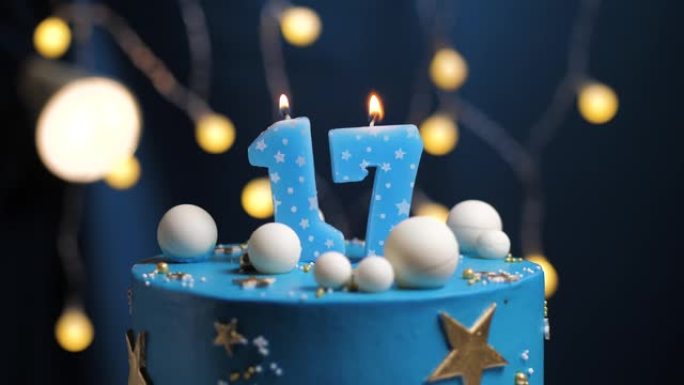 17号生日蛋糕星星天空和月亮概念，蓝色蜡烛被打火机点燃，然后吹灭。如果需要，请在屏幕右侧复制空间。特