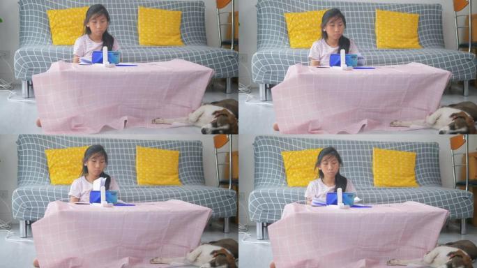 亚洲女孩在家在线学习家庭教育，她的狗睡在地板上，检疫生活方式的概念