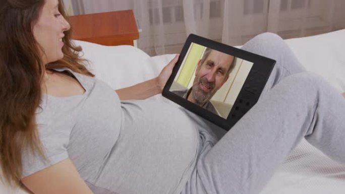 年轻的成年女性女儿在笔记本电脑屏幕上打电话给年长的父亲。女人通过网络摄像头说话。视频电话，家庭聊天概