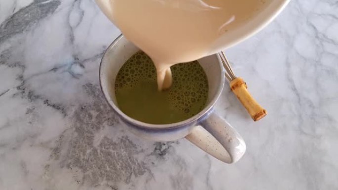 Pouring milk in matcha tea making拿铁