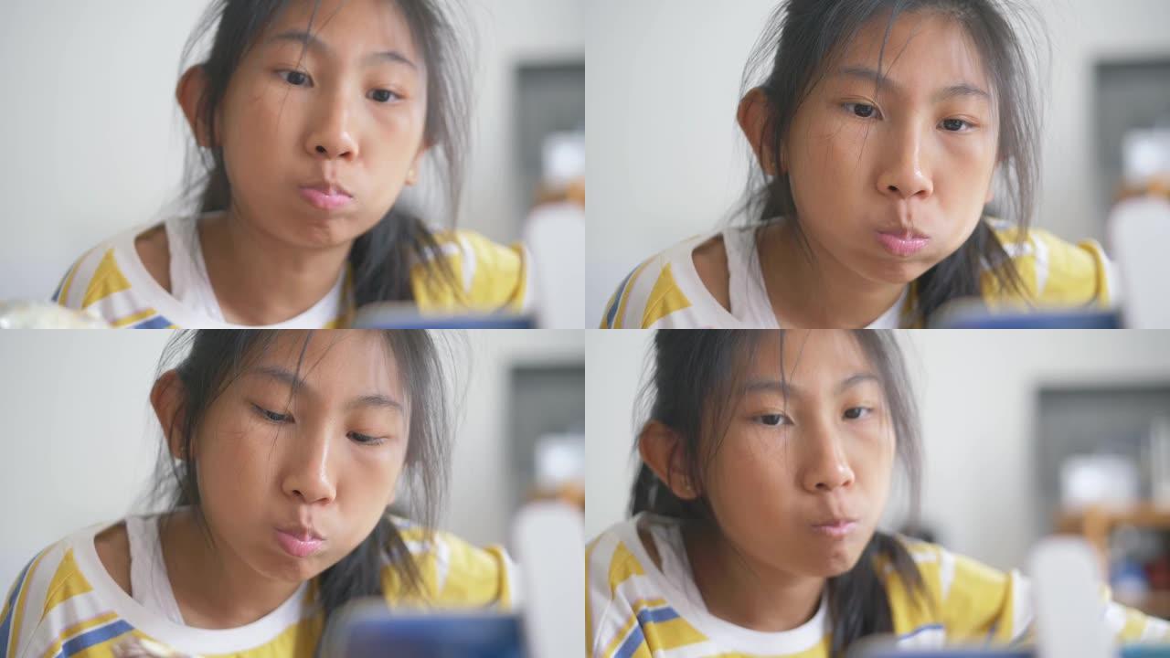 亚洲女孩在家里的窗户附近吃玉米蛋黄包 (玉米面包)，慢动作。