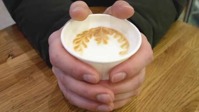 一个男人用热咖啡温暖双手。