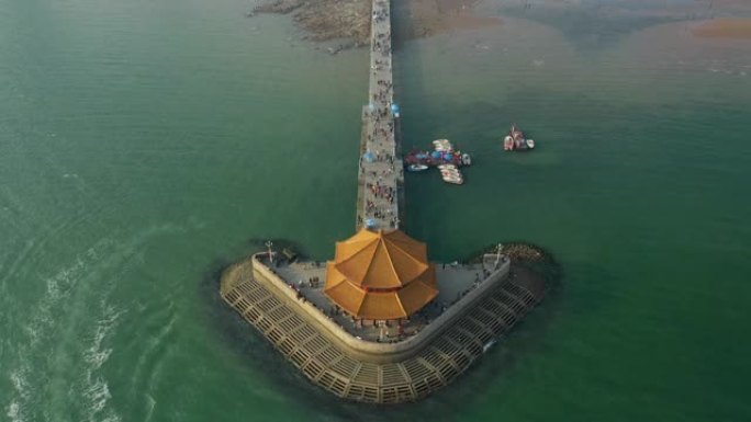阳光明媚的夜晚青岛市著名的海滩海湾宝塔拥挤的码头空中全景4k中国