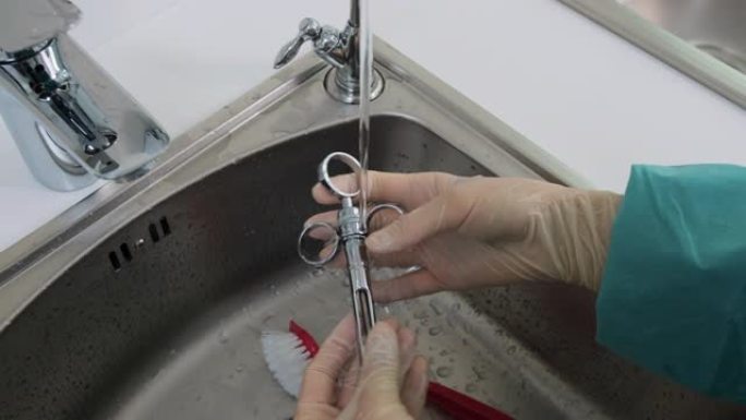 护士用手在蒸馏水下清洗牙科工具的特写镜头