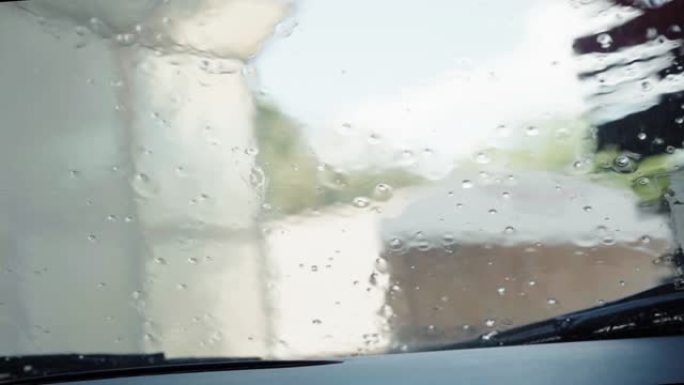 潮湿的汽车挡风玻璃，水泡和水滴从窗户流下。自动洗车机，大刷子旋转和清洁车窗和外部。FHD汽车清洁公共