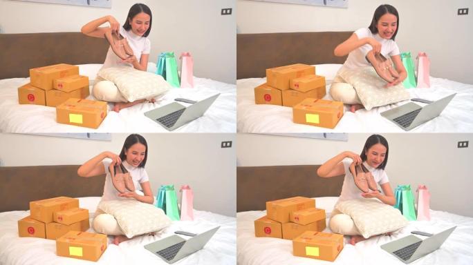 亚洲年轻女子与顾客交谈，在家里的床上在线展示和销售产品，同时坐在前置摄像头中录制视频并通过互联网向社