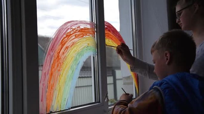 女孩和男孩在家里新型冠状病毒肺炎检疫时在窗户上画彩虹。居家社交媒体预防冠状病毒运动