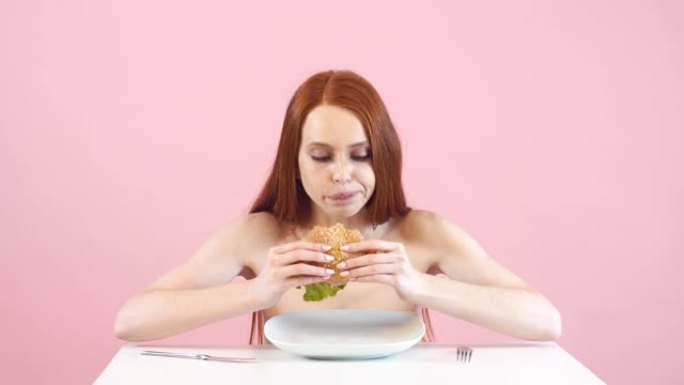 快乐厌食症女孩贪婪地吃汉堡。违反饮食。厌食症