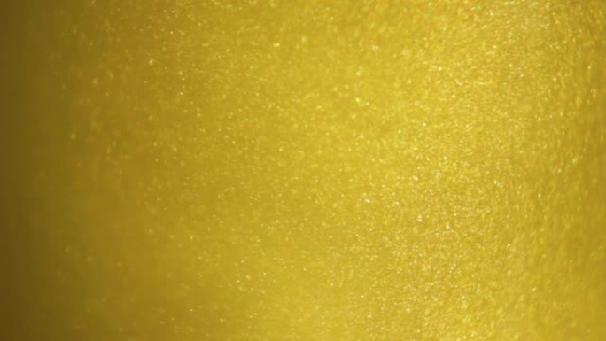 金色墨水灰尘漂浮在液体中。金色闪光的沙子在水中旋转