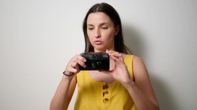 穿着黄色t恤的女摄影师在旧的塑料相机上拍摄肥皂碟