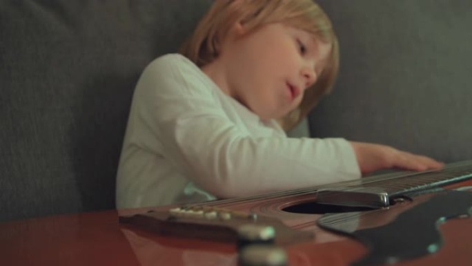 蹒跚学步的男孩在沙发上弹吉他