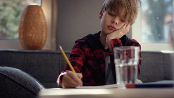 无聊的十几岁的男孩躺在手上写字