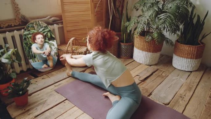 女人在家里练习瑜伽时从头到膝盖向前弯曲