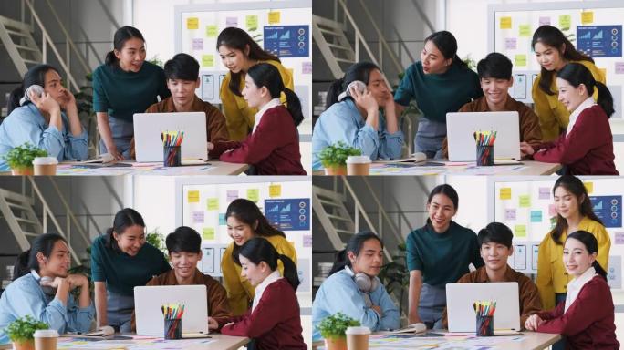 亚洲ux/ui设计师集思广益，讨论桌子上的移动应用界面线框设计，并在现代办公室抬头看相机。创意数字发