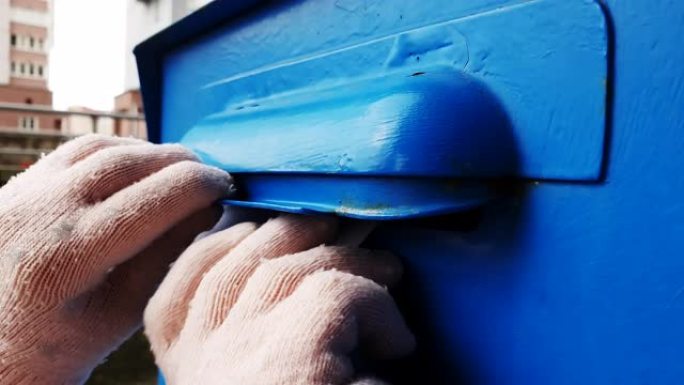 孩子们的手的特写镜头在蓝色的邮箱里扔了一封信。
