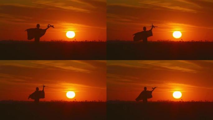 一个男孩手里拿着一架飞机跑过田野。美丽的日落。4K