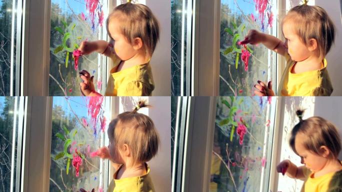 蹒跚学步的女孩正在窗户上画画，唱歌。孩子在家的概念。检疫