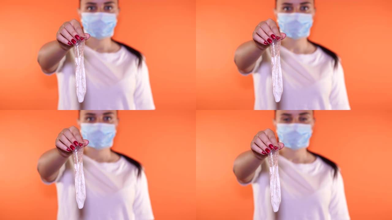 一个医生的手用过的避孕套和精子在一个橙色的背景。精子乳胶和防止怀孕