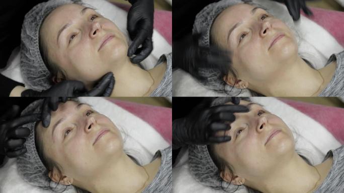 美容师在美容诊所沙龙的女性脸上涂抹保湿霜