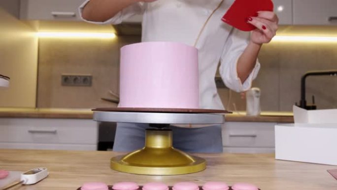 女人面包师正在厨房里做一个美味的粉红色蛋糕
