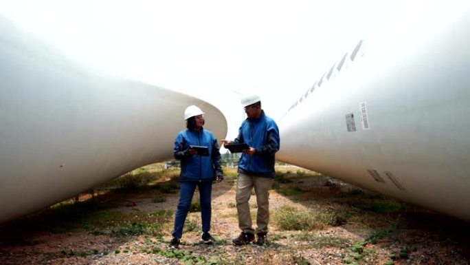 两位亚洲工程师正在检查风力涡轮机的系统