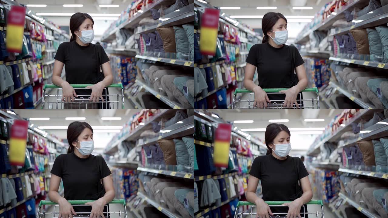 新型冠状病毒肺炎大流行期间，慢动作亚洲女士在超市购物中心戴口罩推购物车。年轻女士储备物资，反检疫和社