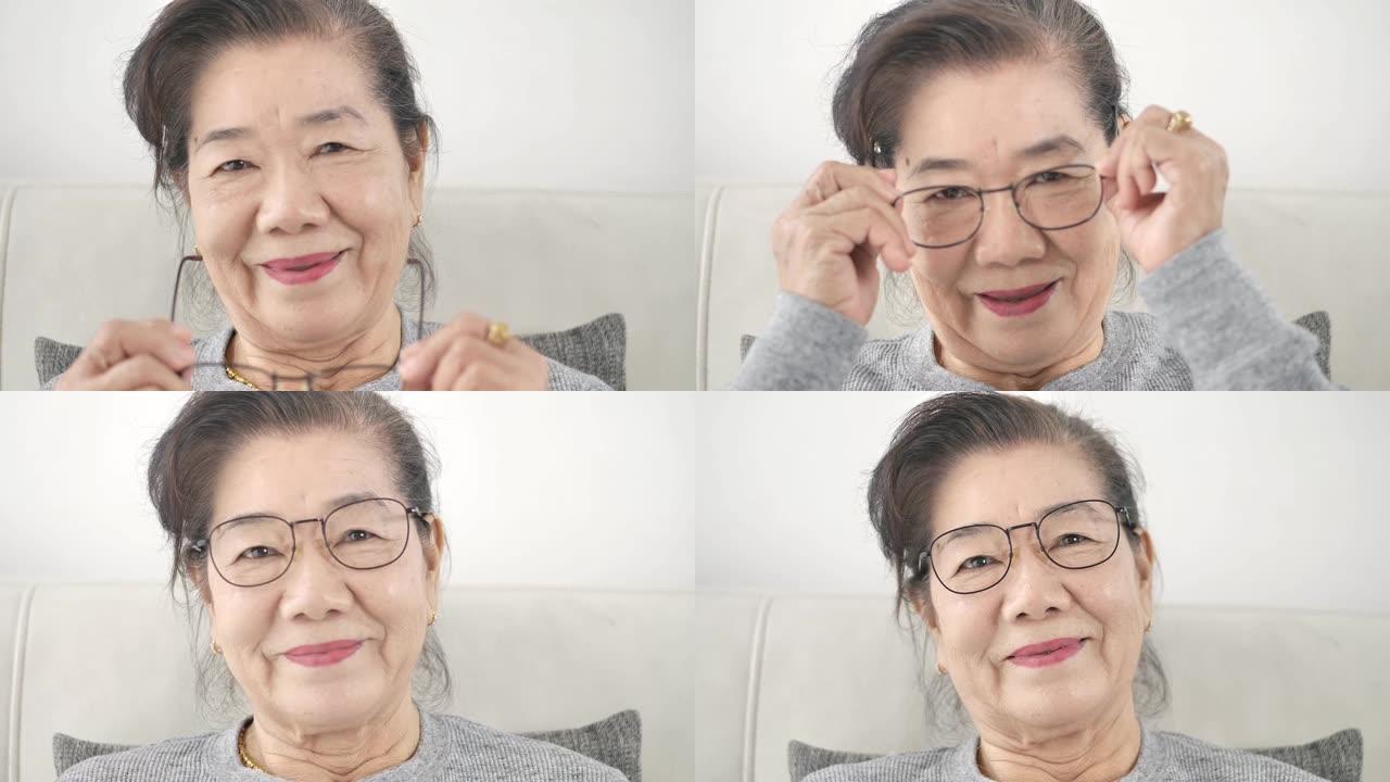 快乐的亚洲高级女性戴着眼镜，坐在家里的沙发上，慢动作。