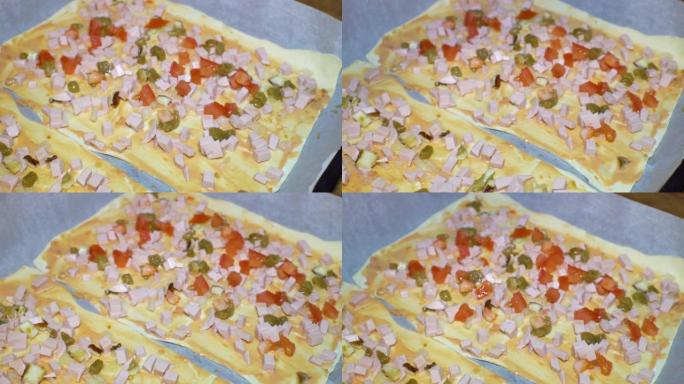 用番茄酱、香肠、黄瓜和番茄烹饪比萨饼。厨师的工作。厨师安排了切成薄片的番茄比萨饼和奶酪和香肠。