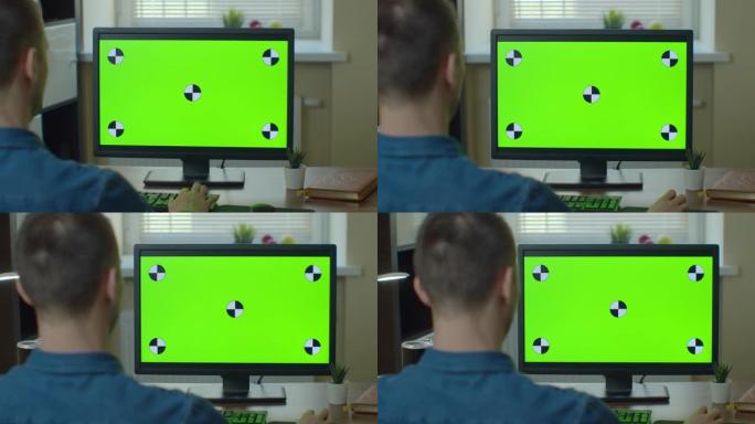 男性视频编辑器可以在他的个人计算机上使用绿色大屏幕模拟显示。