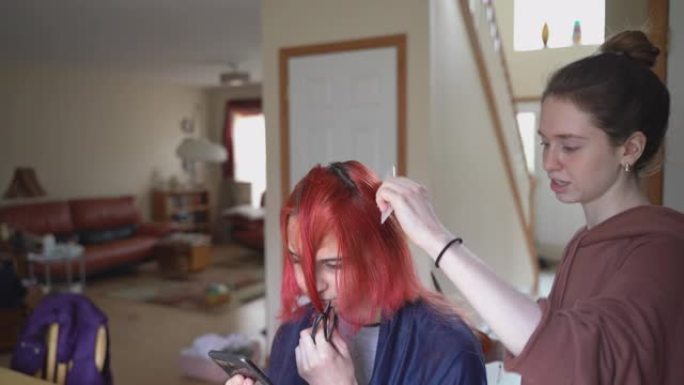 姐姐在家里剪了妹妹的头发，而她正在与朋友视频聊天，并在网上直播理发的过程。