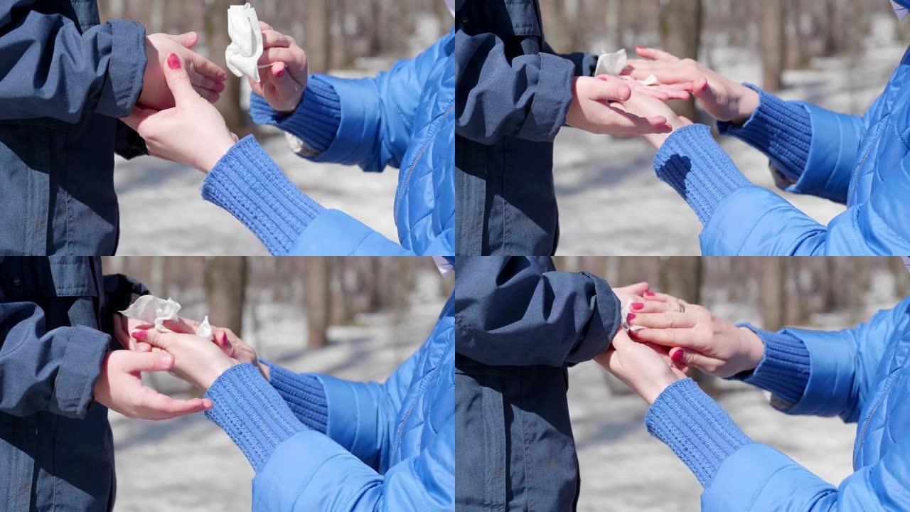 一个女孩在街上用抗菌抹布擦拭孩子的手。预防和保护健康和生命安全。