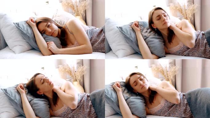 女人有失眠女孩睡眠不好，脖子和脊柱疼痛，因为睡觉不舒服的枕头和床垫，年轻漂亮的女孩穿着睡衣躺在床上盖